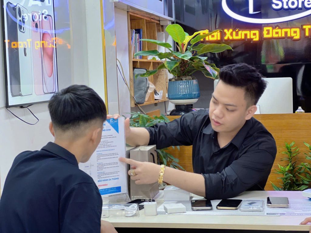 Nhân viên Táo 247 đang tư vấn chính sách bảo hành cho khách hàng sau khi mua iPhone, thể hiện sự minh bạch và cam kết hậu mãi tại cửa hàng.