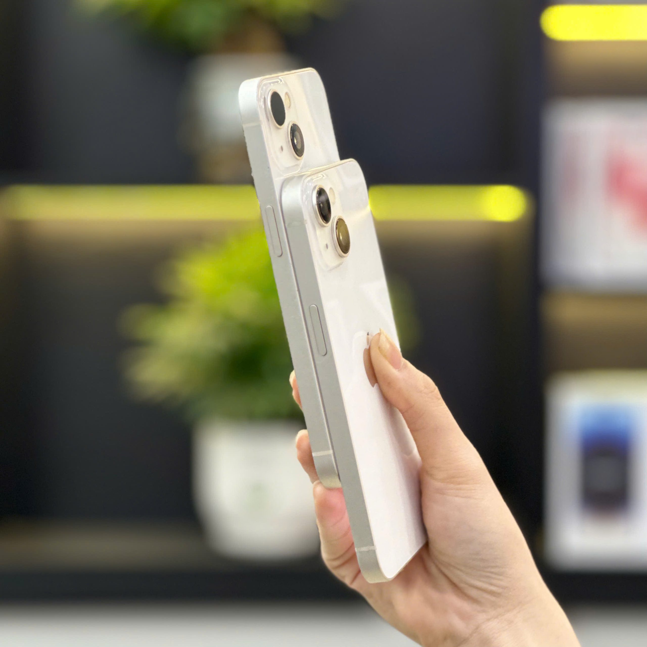 Khách hàng cầm trên tay 2 chiếc iPhone 99% cũ màu trắng tại Táo 247 Đà Nẵng