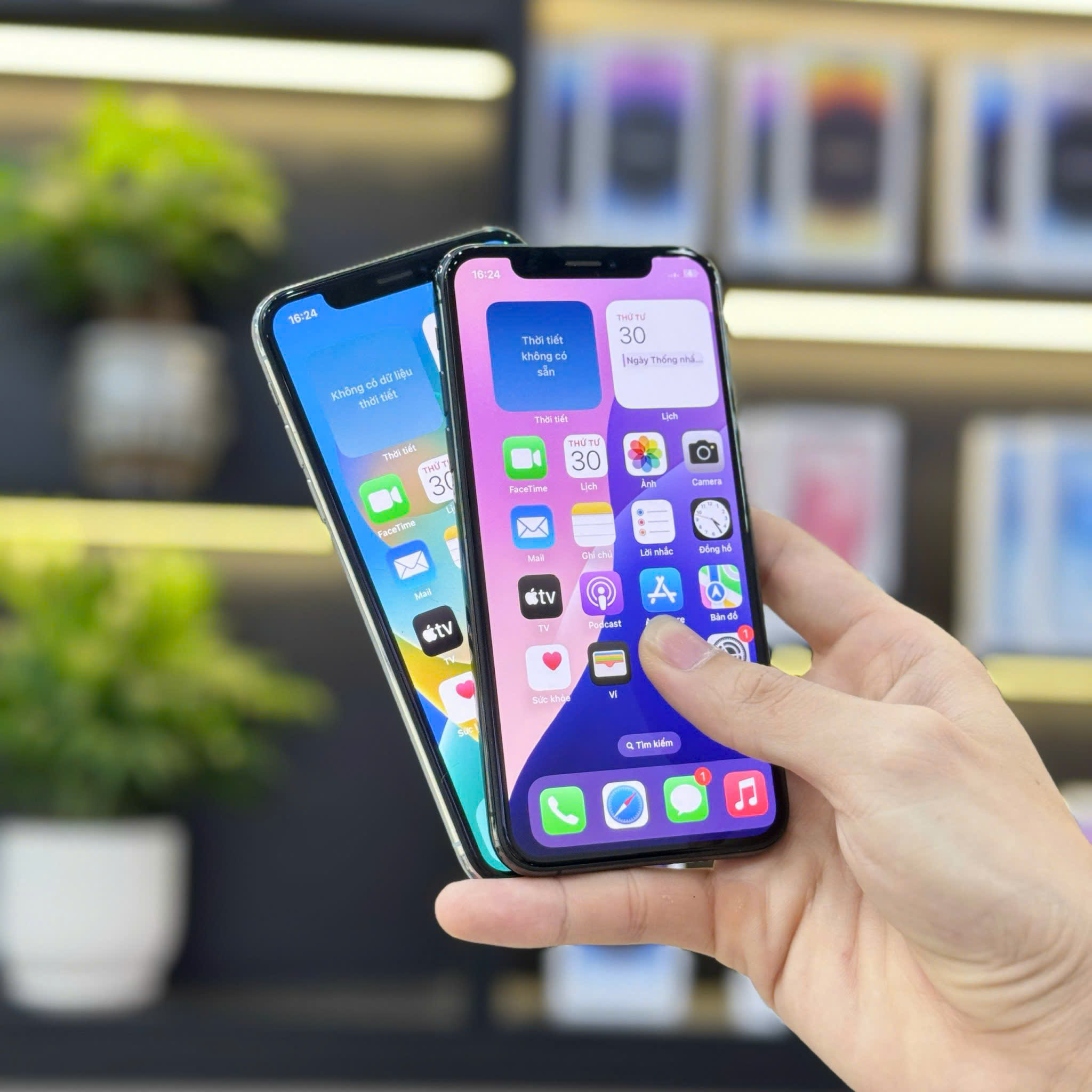 Người cầm trên tay hai chiếc iPhone XS Max cũ, chụp tại cửa hàng điện thoại ở Đà Nẵng.