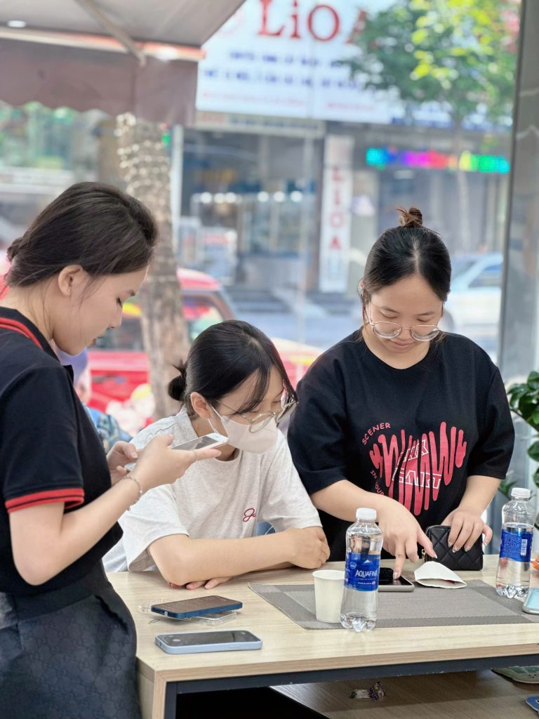 Khách hàng nữ trải nghiệm iPhone cũ tại Táo 247 Đà Nẵng cùng nhân viên tư vấn
