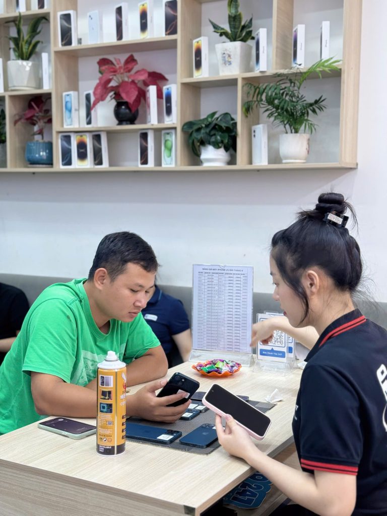 Khách hàng kiểm tra iPhone cũ cùng nhân viên tư vấn tại cửa hàng Táo 247 Đà Nẵng
