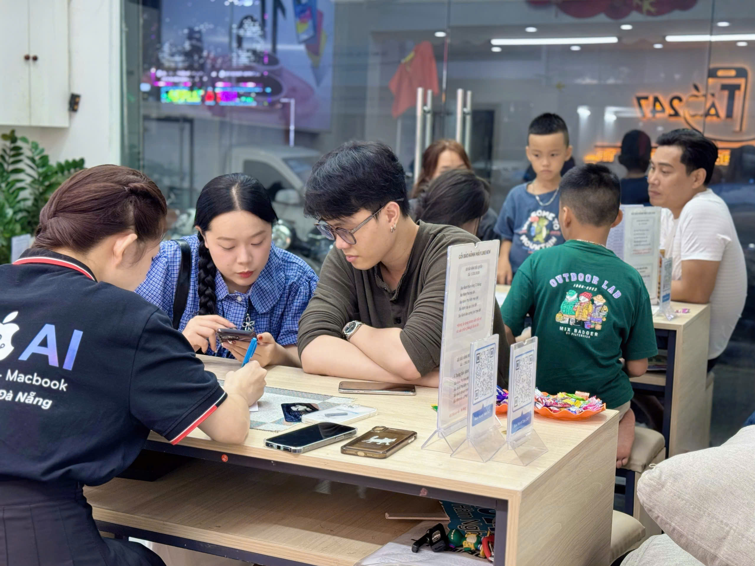 "Khách hàng đang trải nghiệm và mua iPhone tại cửa hàng Táo 247 Đà Nẵng – Không khí đông đúc, tư vấn tận tâm, uy tín hàng đầu."
