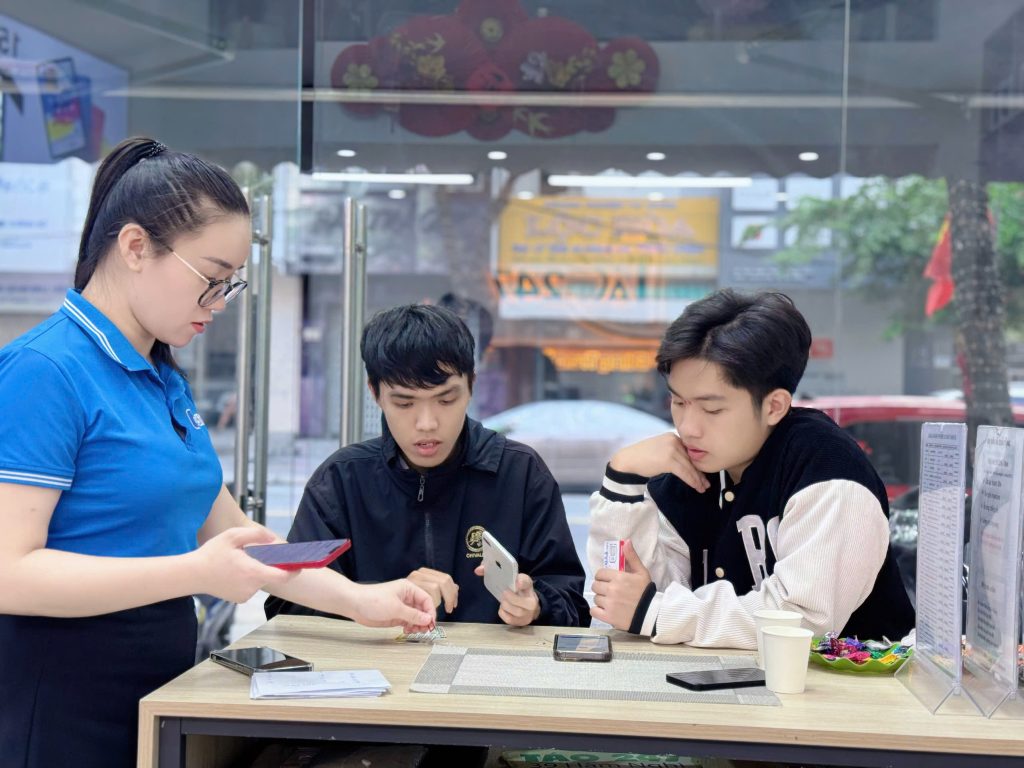 Nhân viên Táo 247 tư vấn và hỗ trợ khách kiểm tra iPhone cũ tại cửa hàng Đà Nẵng
