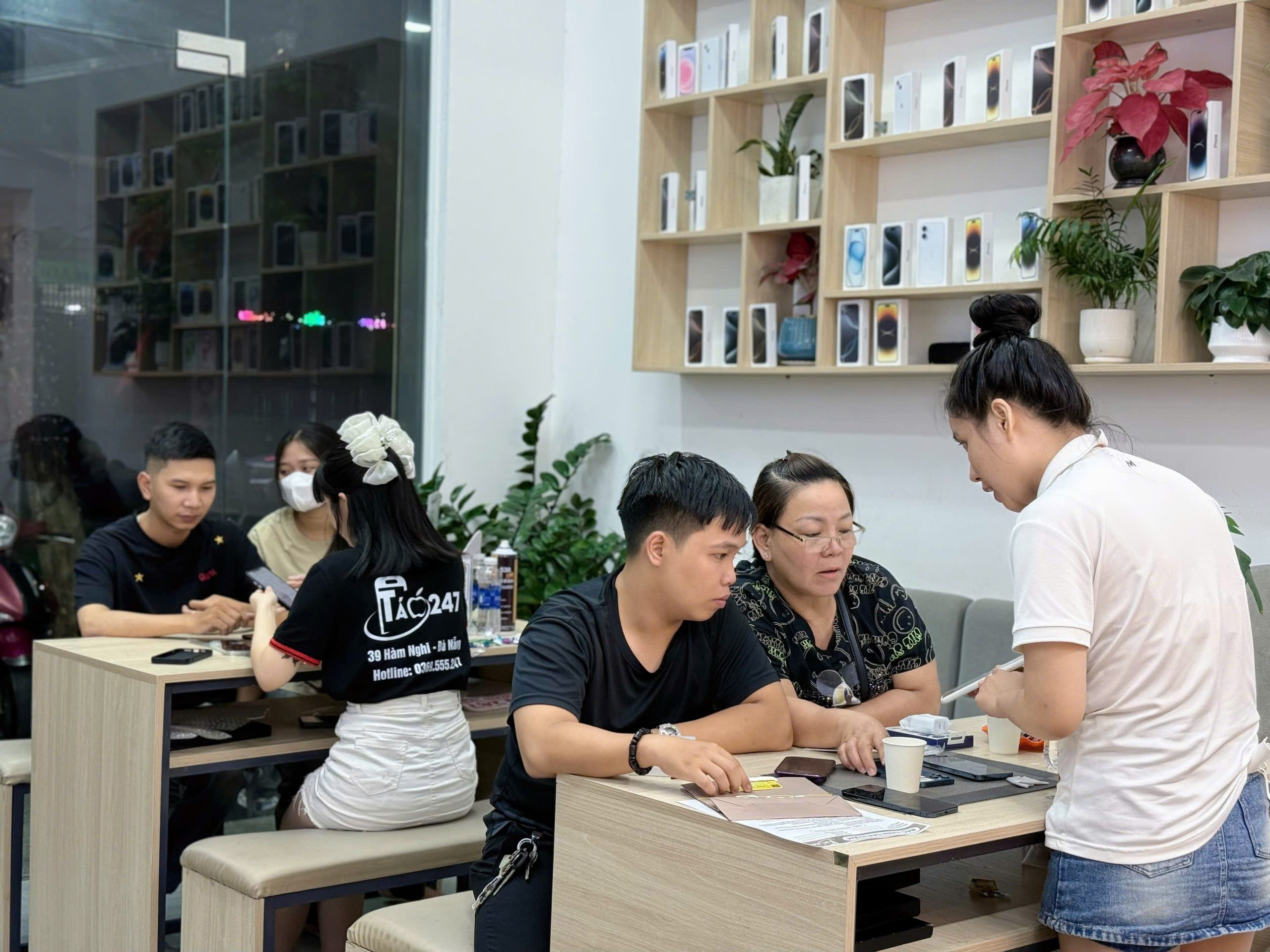Khách hàng đang được nhân viên Táo 247 Đà Nẵng tư vấn và hỗ trợ kiểm tra iPhone cũ tại cửa hàng – không gian chuyên nghiệp, minh bạch.