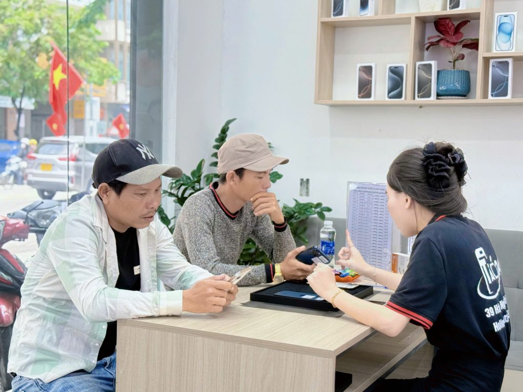 Khách hàng kiểm tra iPhone cũ tại cửa hàng Táo 247 Đà Nẵng cùng nhân viên tư vấn