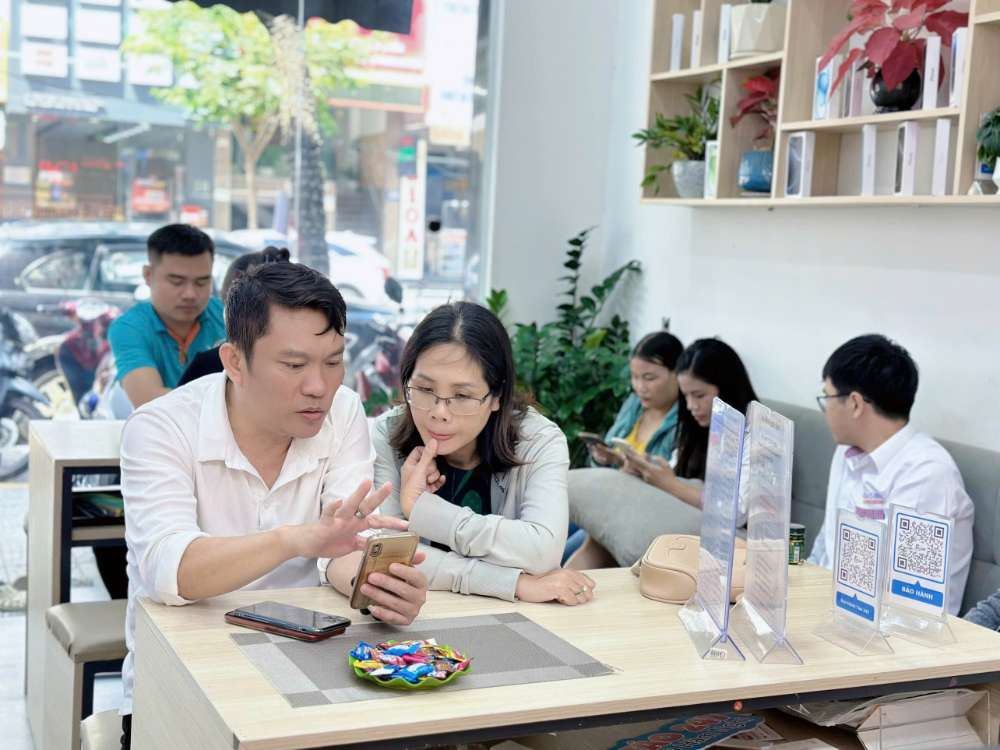 Nhân viên Táo 247 Hồ Chí Minh hướng dẫn khách hàng trải nghiệm iPhone cũ tại cửa hàng