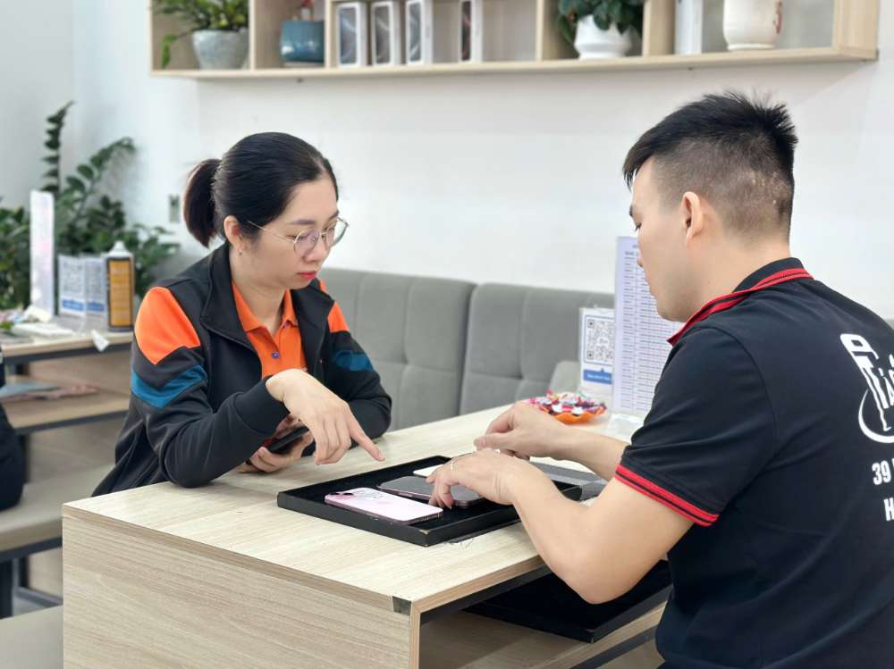 Nhân viên Shop Táo 247 Hồ Chí Minh đang hướng dẫn khách hàng test iPhone cũ zin 100% trước khi mua