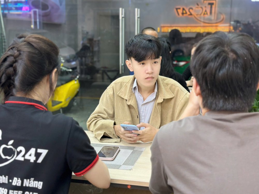 Khách hàng đang kiểm tra iPhone cũ xách tay giá rẻ tại cửa hàng Táo 247 Gò Vấp, TP Hồ Chí Minh