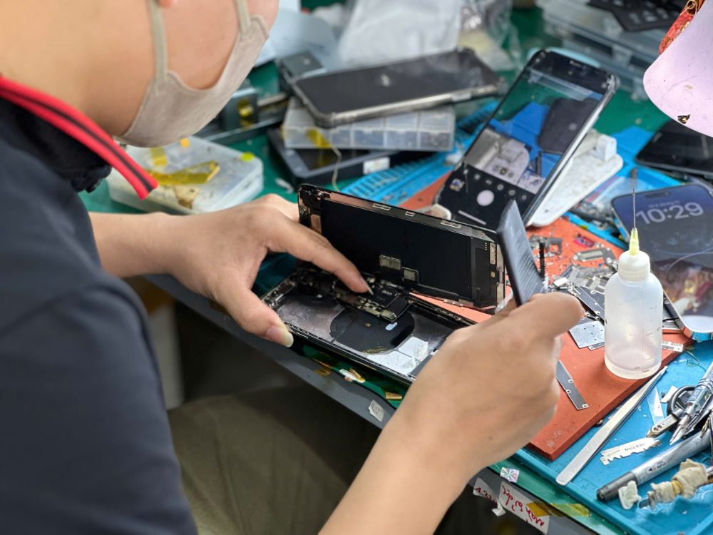 Kỹ thuật viên Táo 247 đang kiểm tra và sửa chữa iPhone trực tiếp cho khách hàng