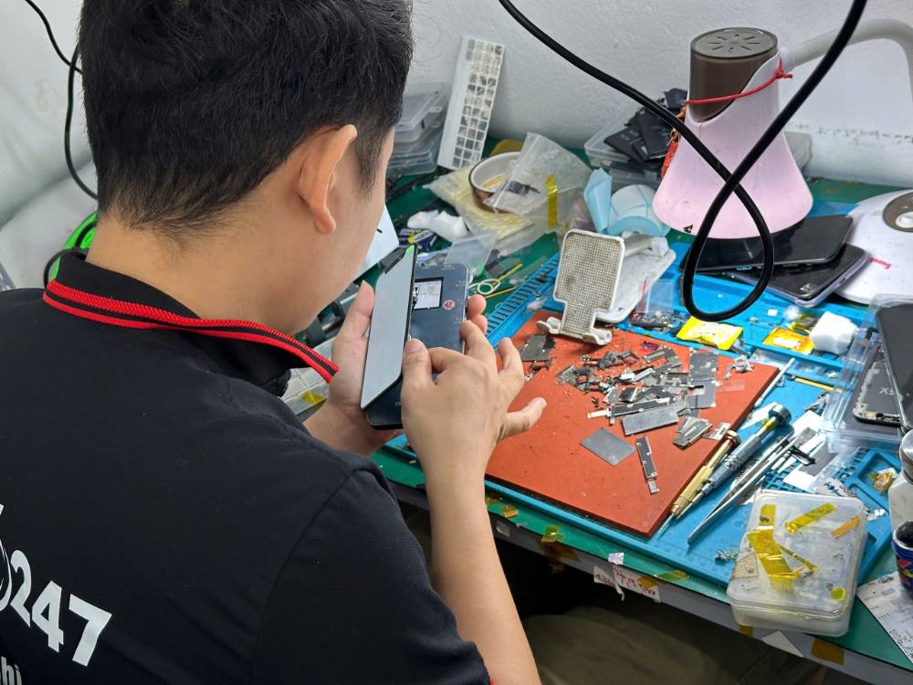 Kỹ thuật viên Táo 247 đang sửa chữa iPhone bằng thiết bị chuyên dụng