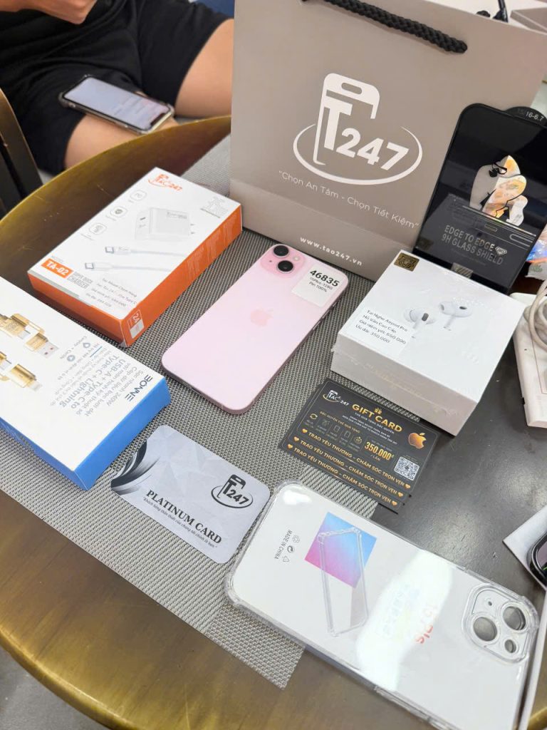 iPhone 15 Plus màu hồng cùng thẻ Platinum và phụ kiện trên bàn tư vấn Táo 247