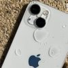 iPhone màu trắng bám giọt nước trên nền cát sau khi bị rơi nước