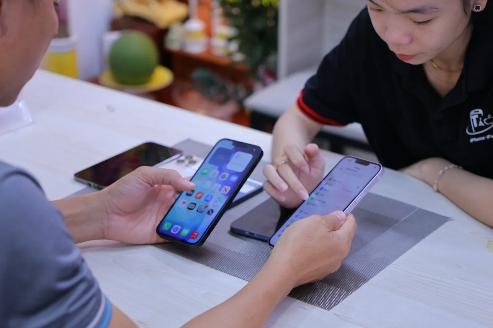 Khách và nhân viên Táo 247 cùng xem màn hình chính của hai chiếc iPhone trên bàn