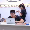 Kỹ thuật viên Táo 247 làm việc với MacBook tại quầy, đồng nghiệp đứng phía sau