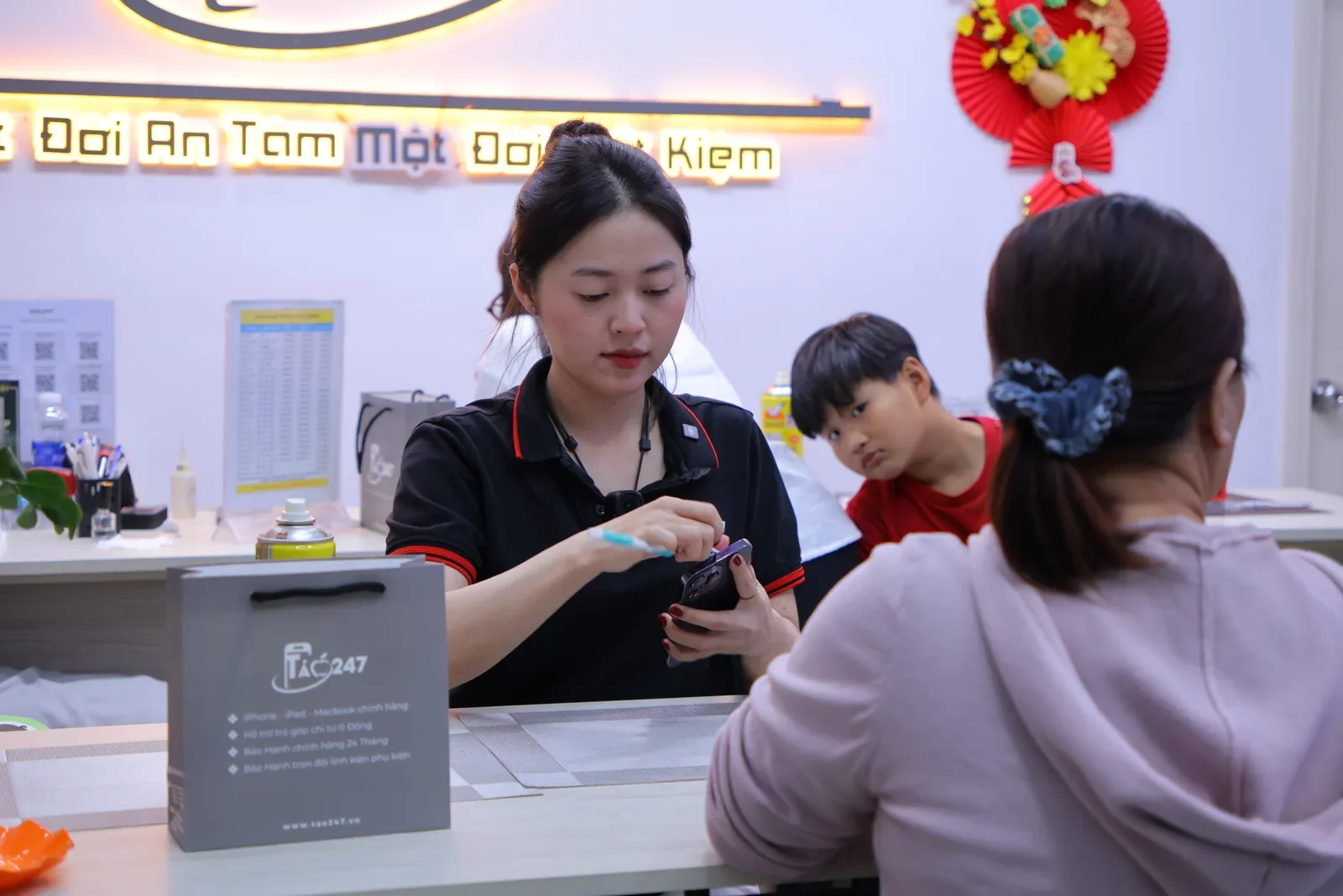 Nhân viên Táo 247 dán kính cường lực cho khách tại quầy