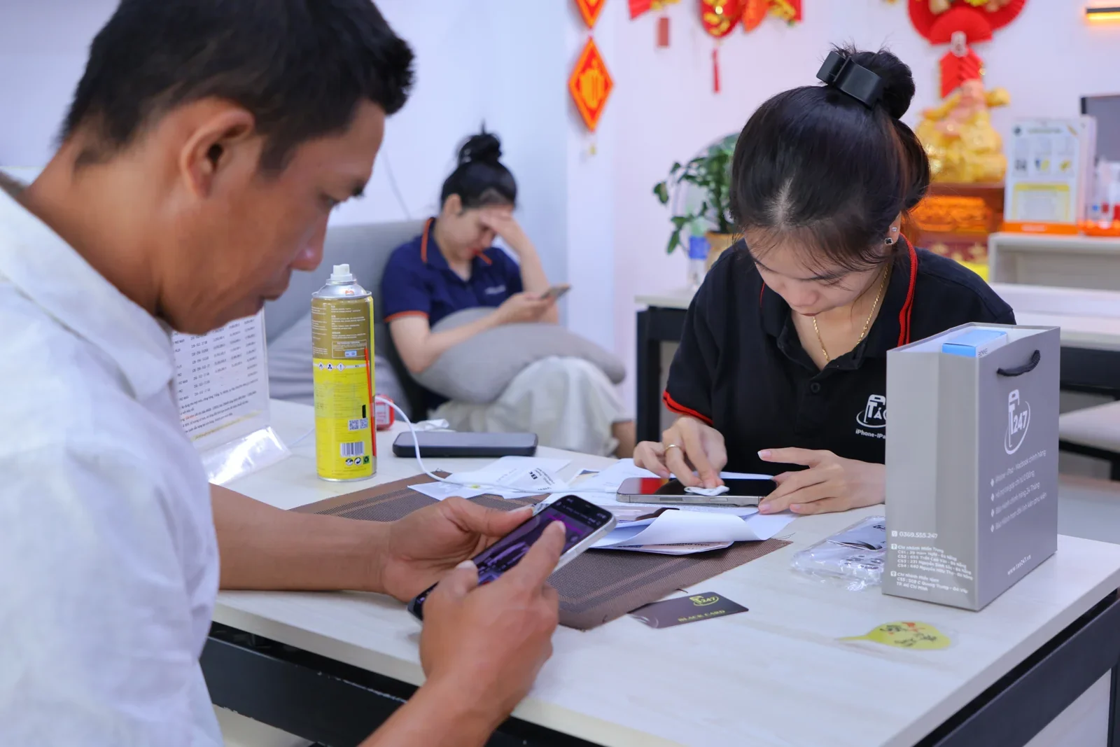 Nhân viên Táo 247 vệ sinh màn hình máy trong lúc khách tự kiểm tra iPhone tại bàn