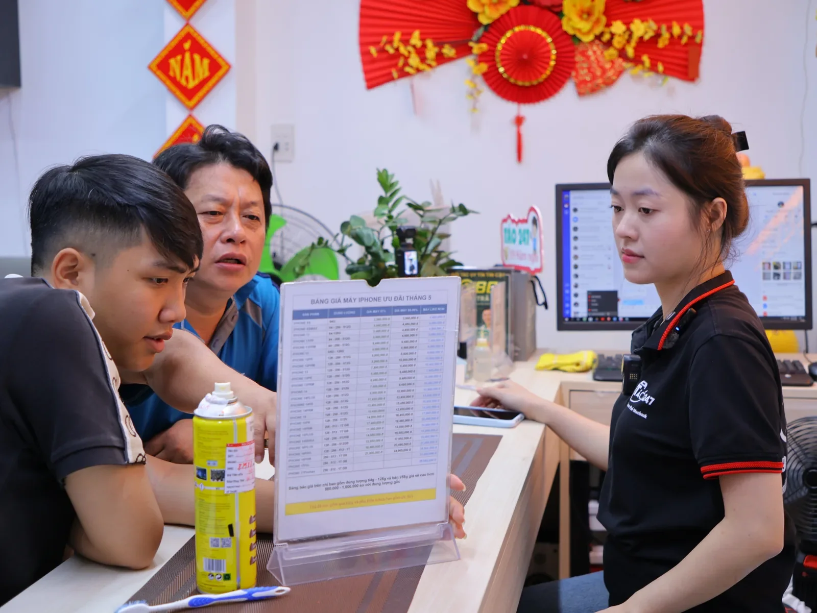 Nhân viên Táo 247 giới thiệu bảng giá cho hai khách nam tại quầy