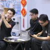 Nhân viên Táo 247 soi màn hình iPhone trước mặt hai khách